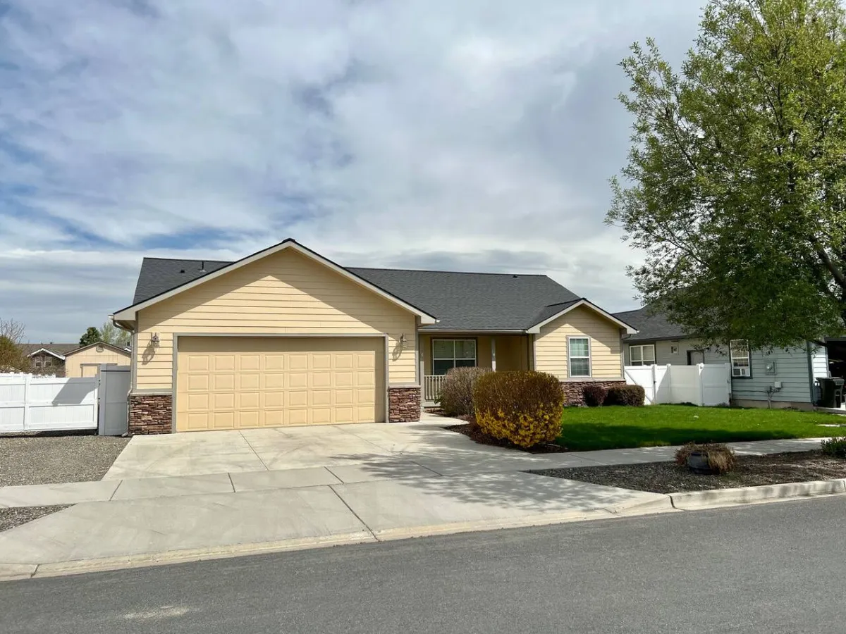 The exterior front of the house showing the private driveway, garage door, landscaped yard, and entry pathway. The scene is inviting, emphasizing dedicated parking and attractive curb appeal.