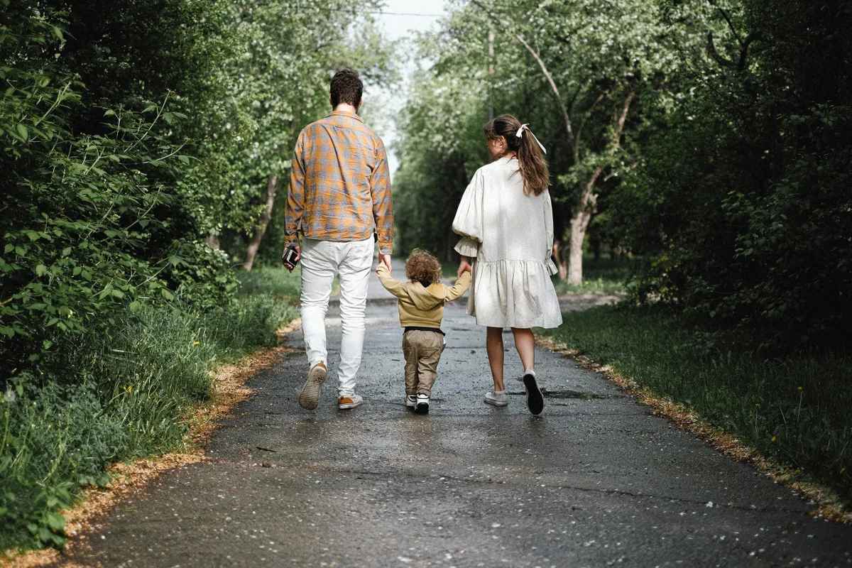 A cheerful exterior shot featuring a family walking together along a tree-lined pathway, surrounded by greenery. The atmosphere is lively and joyful, emphasizing family bonding and the spirit of adventure in the outdoors.