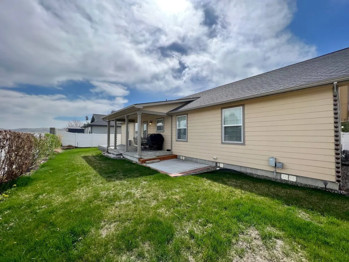 A welcoming image of the home's exterior, showcasing the house, porch area, green lawn, and a cloudy sky. The scene feels inviting and highlights the comfortable, accessible entrance and the sense of arriving at a home base for your group.