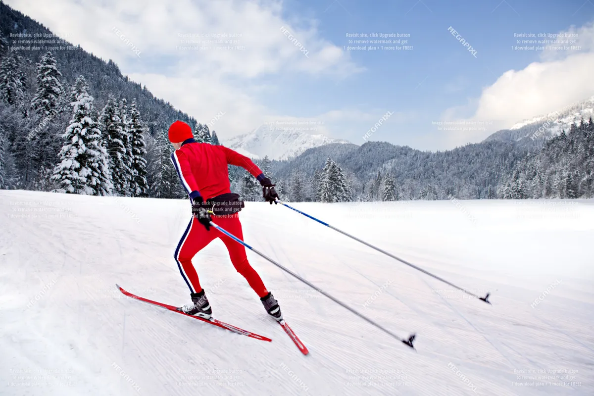 A skier dressed in bright red glides across a pristine, snow-covered landscape lined with pine trees, evoking the exhilaration of winter sports and the beauty of the surrounding wilderness.